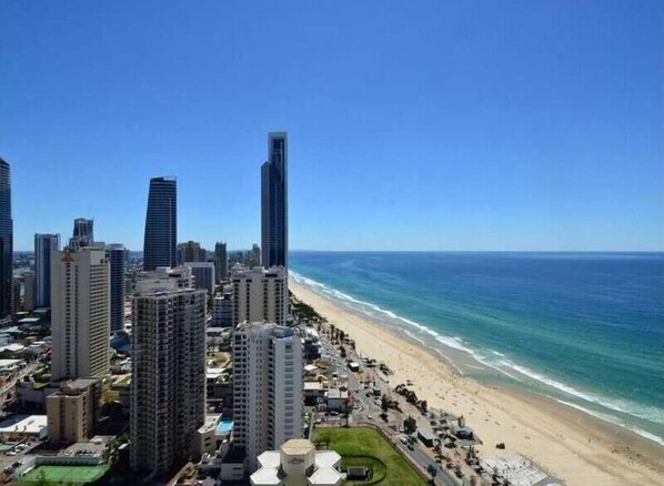 Un paysage urbain côtier avec de hauts immeubles, une plage et un ciel bleu dégagé.