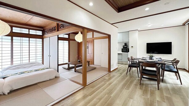 Une pièce de style japonais traditionnel, avec un sol recouvert de tatamis, une table basse avec des coussins et des portes coulissantes.