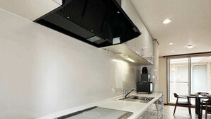 Une cuisine moderne dotée d’une cuisinière intégrée, d’une hotte noire et d’un coin repas avec une table et des chaises.