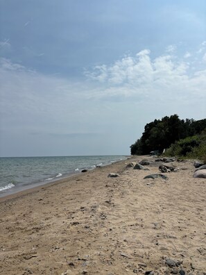 A sandy beach with scattered rocks and a calm sea.