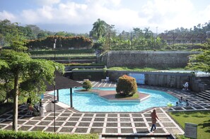 Una piscina con bordo piastrellato, circondata da vegetazione e un muro in pietra.