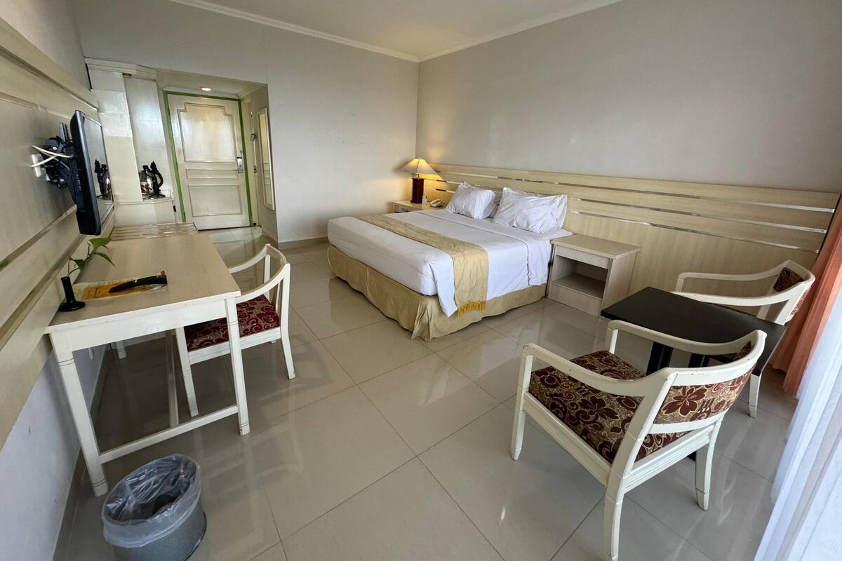 Une chambre d’hôtel équipée d’un lit, d’un bureau, d’une chaise, d’une télévision et d’une poubelle.