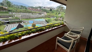 A balcony with a view of a swimming pool, a tennis court, and a lush green landscape. - Queen Garden Hotel by Salak Hospitality (Baturaden)