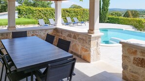 An outdoor patio with a pool, stone walls, and a view of the landscape.