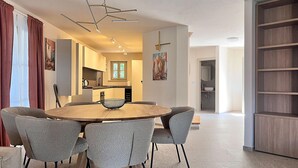A modern dining area with a round table, grey upholstered chairs, and a contemporary light fixture.