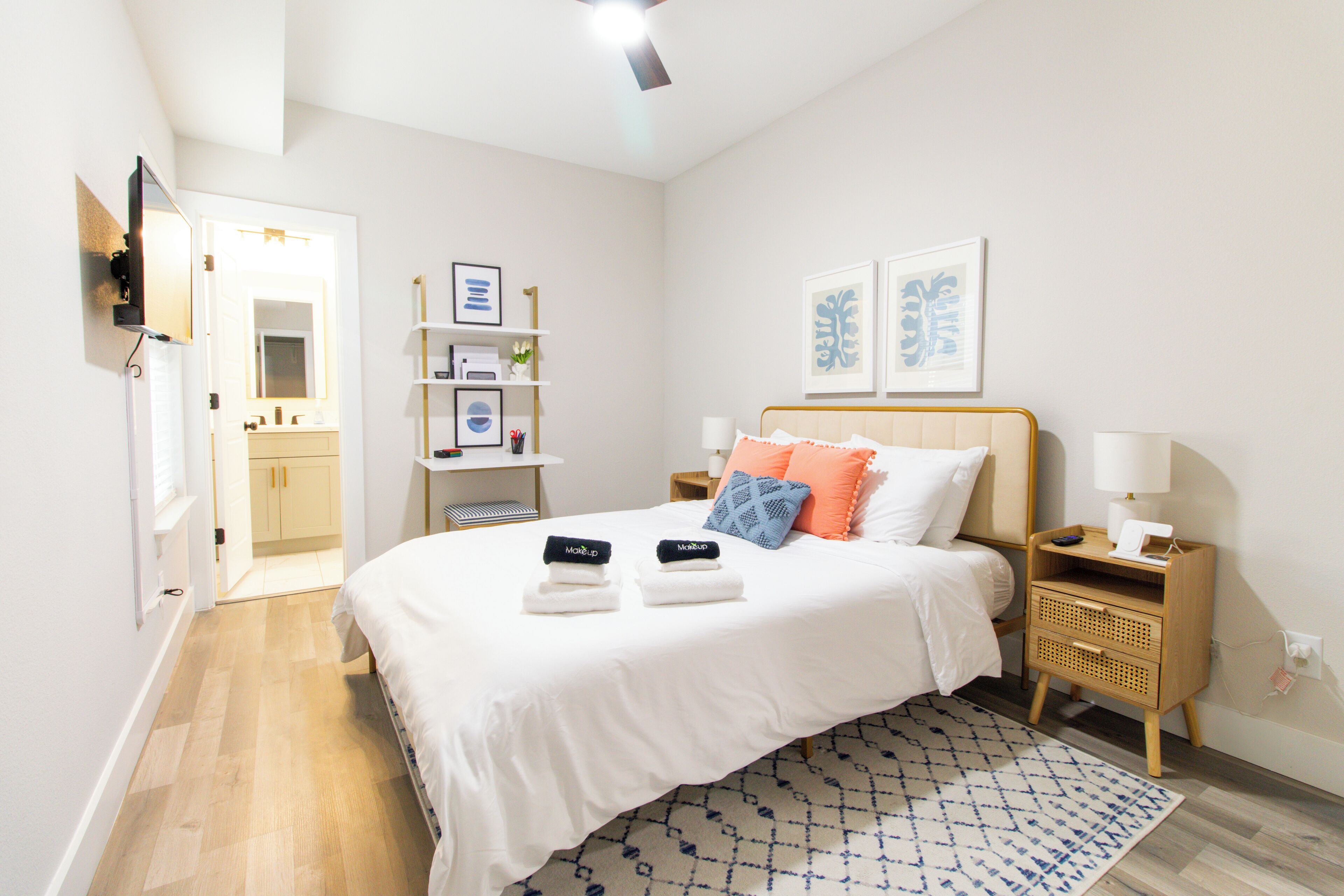Un dormitorio con cama, mesitas de noche, estantería y una puerta que da a otra habitación.