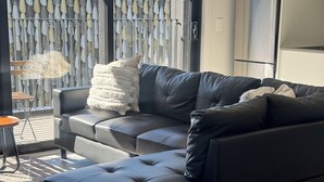 A modern living room with a black leather sofa, a matching ottoman, and a small side table. - 2 Bedroom Luxury apartment plus underground parking in Christchurch CBD (Christchurch)