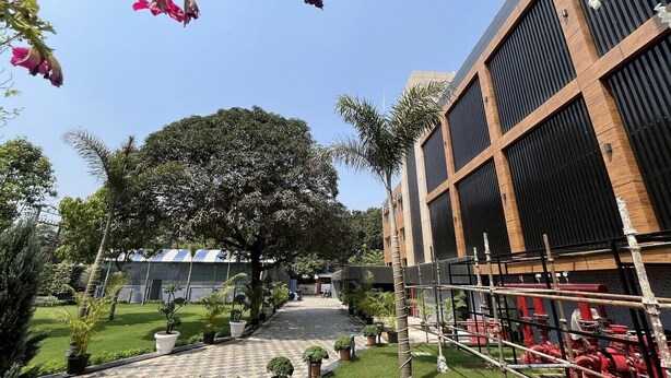 A courtyard with a paved walkway, potted plants, and a building with large windows and a modern design.