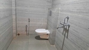 A small, tiled bathroom with a toilet and a shower.