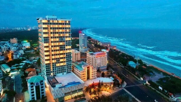 Un hotel moderno de gran altura con varias plantas, un cartel llamativo que dice "CSI Tower" y vistas al océano.