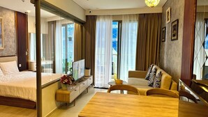 Una habitación de hotel moderna con cama, sofá, mesa de comedor y televisor.