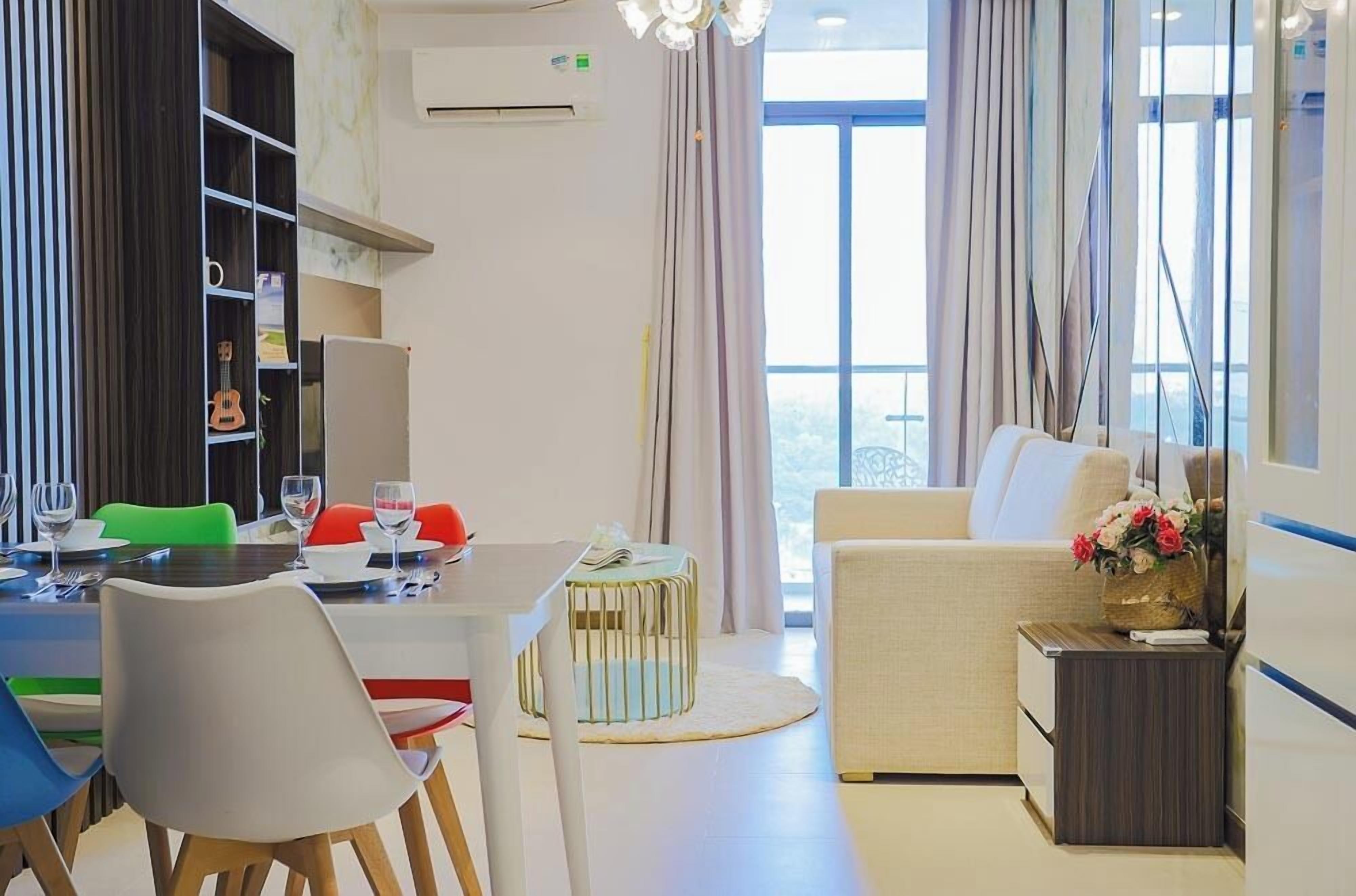A modern living room with a dining area, a sofa, and a small table with a vase of flowers.
