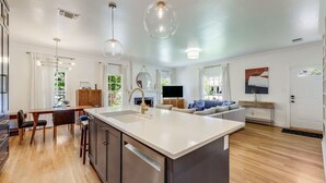 A modern kitchen with a central island, wooden flooring, and pendant lighting. - Pool & Vibes, Relaxing and Fun! (Austin)