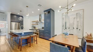 A modern kitchen with a central island, bar stools, and a dining table with chairs. - Pool & Vibes, Relaxing and Fun! (Austin)