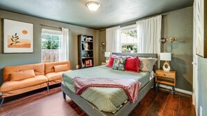 Un dormitorio con cama, sofá, estantería y ventana.
