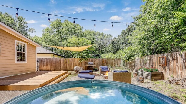 Patio con piscina, mobiliario exterior y cerca de madera.