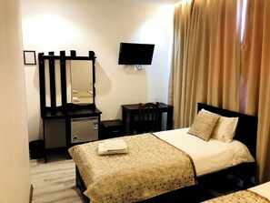 A hotel room with a bed, a desk with a chair, a dresser, a mirror, and a television mounted on the wall. - Maryam Hotel (Samarkand)