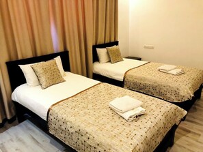 Dos camas individuales con cabeceras y pies de cama iguales, cada una con una colcha y almohadas estampadas.