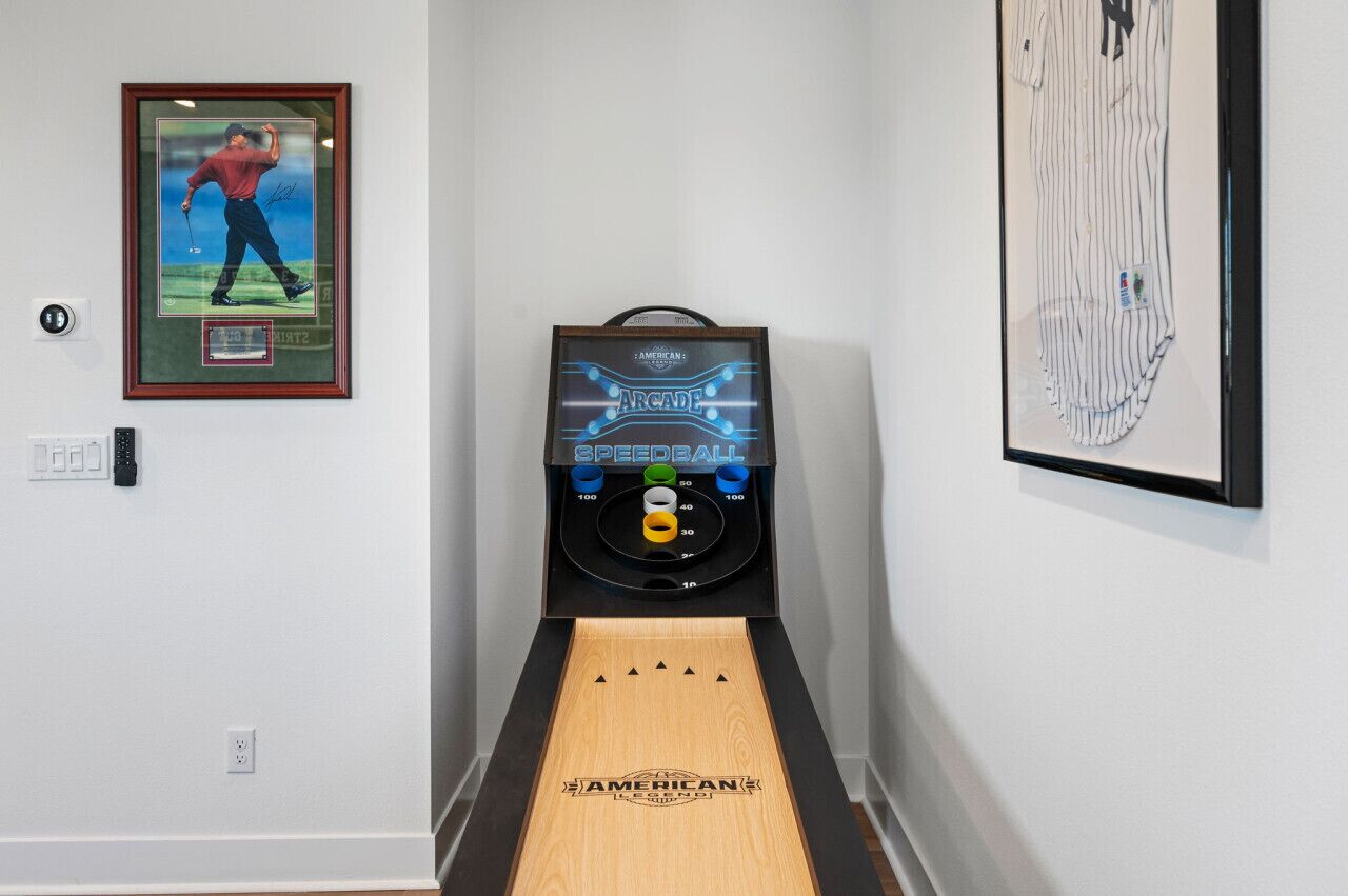 A bowling alley with a framed picture of a golfer and a speedball machine.