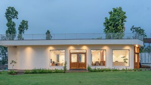A modern two-story house with a flat roof, large windows, and a balcony. - Corbett Four Seasons (Ramnagar)