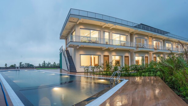 A modern multi-story hotel with a swimming pool, balconies, and a well-maintained garden. - Corbett Four Seasons (Ramnagar)