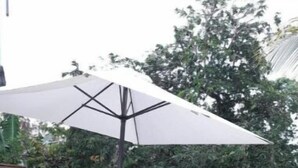 A wooden deck with a table and chairs under a white umbrella. - Le Jasmyna (Sans Pareil)