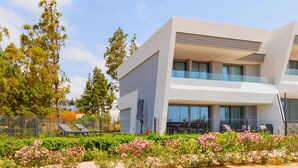 A modern hotel with a flat roof, large windows, and a balcony with outdoor seating.