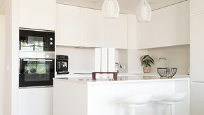 A modern kitchen with white cabinetry, stainless steel appliances, and a central island with bar stools.