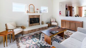 A living room with a fireplace, a sofa, a coffee table, and a patterned rug.