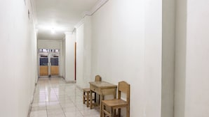 Un pasillo con una mesa y sillas de madera, una puerta al final y suelo de baldosas.