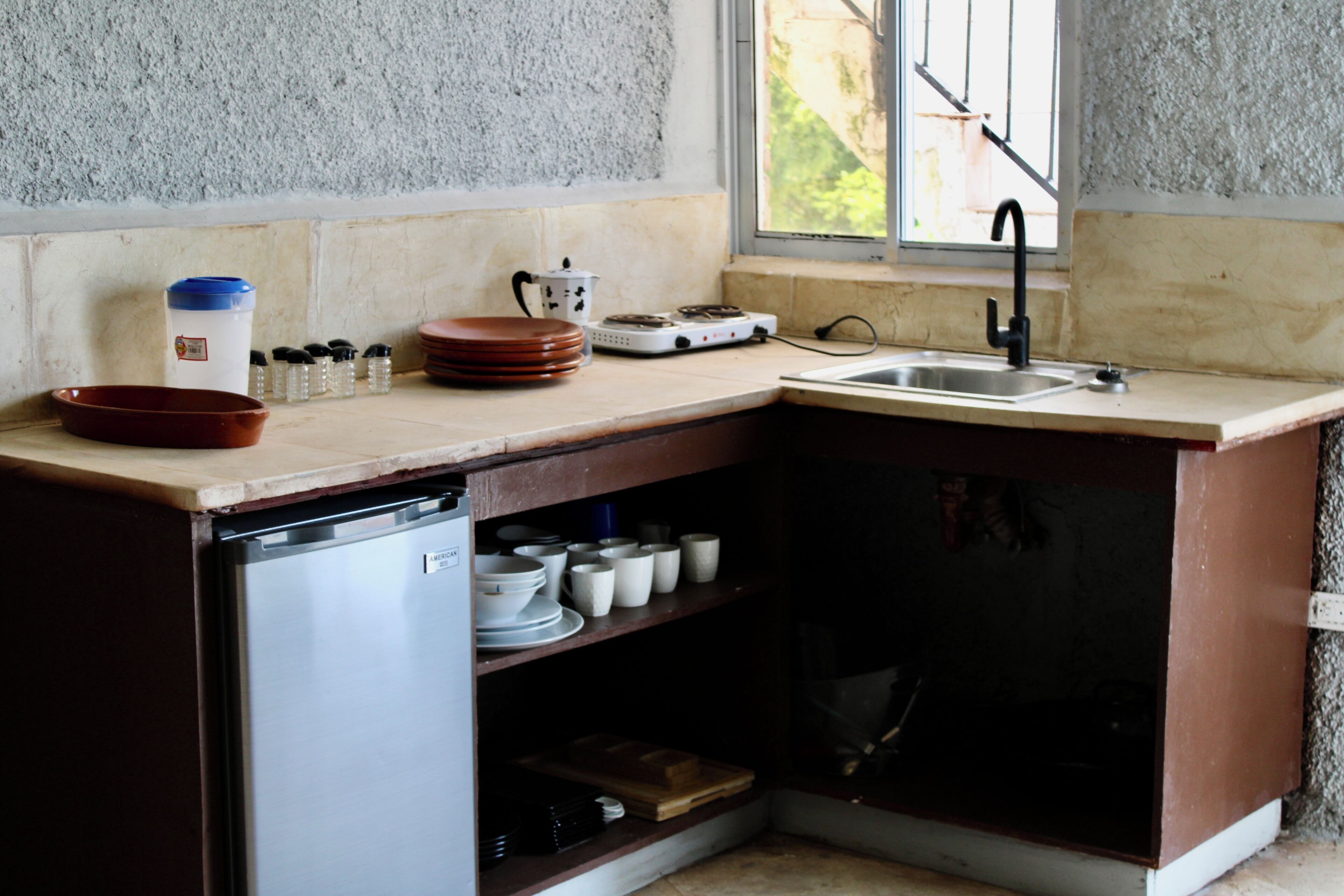 A compact kitchen with a dishwasher, a sink, and a window providing natural light.