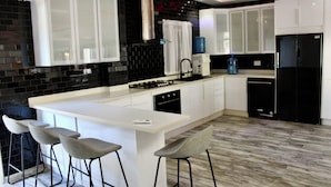 A modern kitchen with a central island, bar stools, and a built-in oven. - Complejo Guayacanes  (Guayacanes)