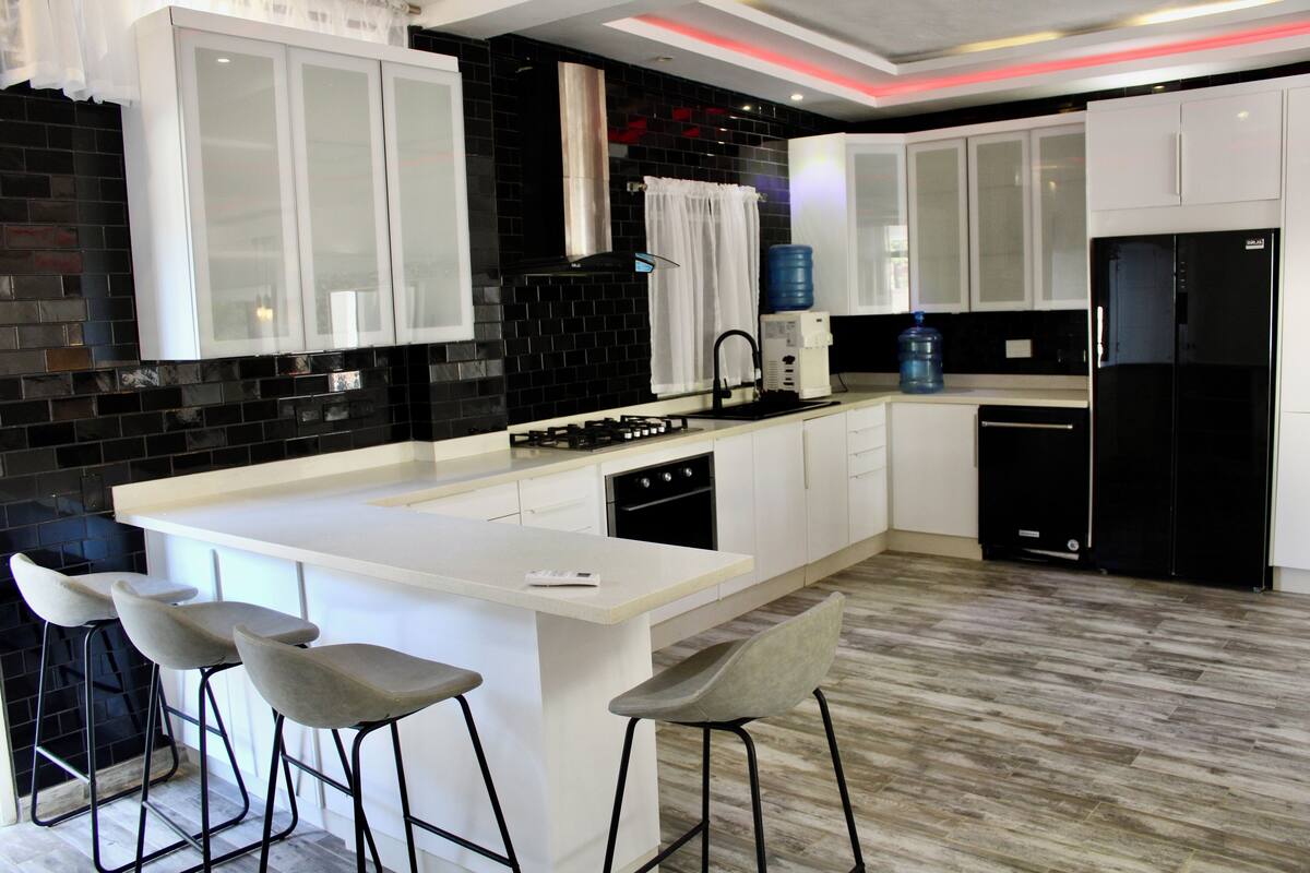 Een moderne keuken met een centraal eiland, barkrukken en een ingebouwde oven.