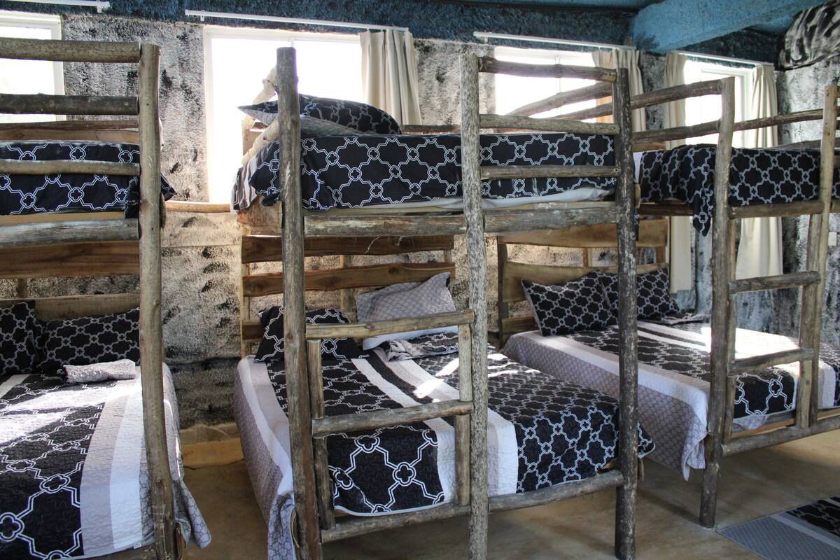 Een slaapkamer met stapelbedden en meerdere bedden, elk met beddengoed met een patroon.