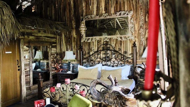 A rustic room with a bed, a nightstand, a lamp, and a decorative mirror. - Complejo Guayacanes  (Guayacanes)