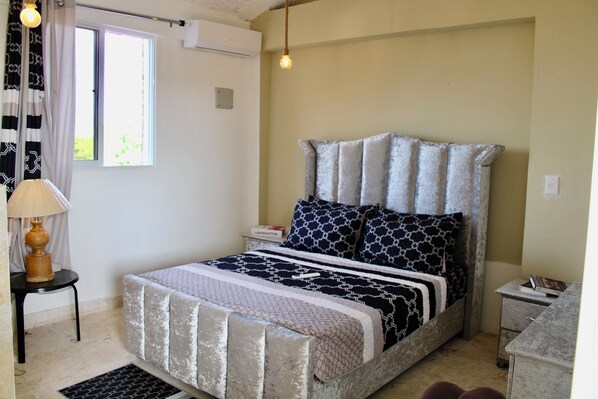 A bedroom with a bed, bedside table, lamp, and a window with curtains. - Complejo Guayacanes (Guayacanes)