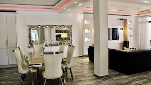 A modern living room with a dining area, featuring a large mirror, white furniture, and a black sofa. - Complejo Guayacanes  (Guayacanes)