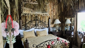 A rustic bedroom with a wooden bed, a mirror, and a fan. - Complejo Guayacanes  (Guayacanes)