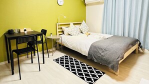 Habitació petita i lluminosa amb un llit, una taula de treball i una cadira.