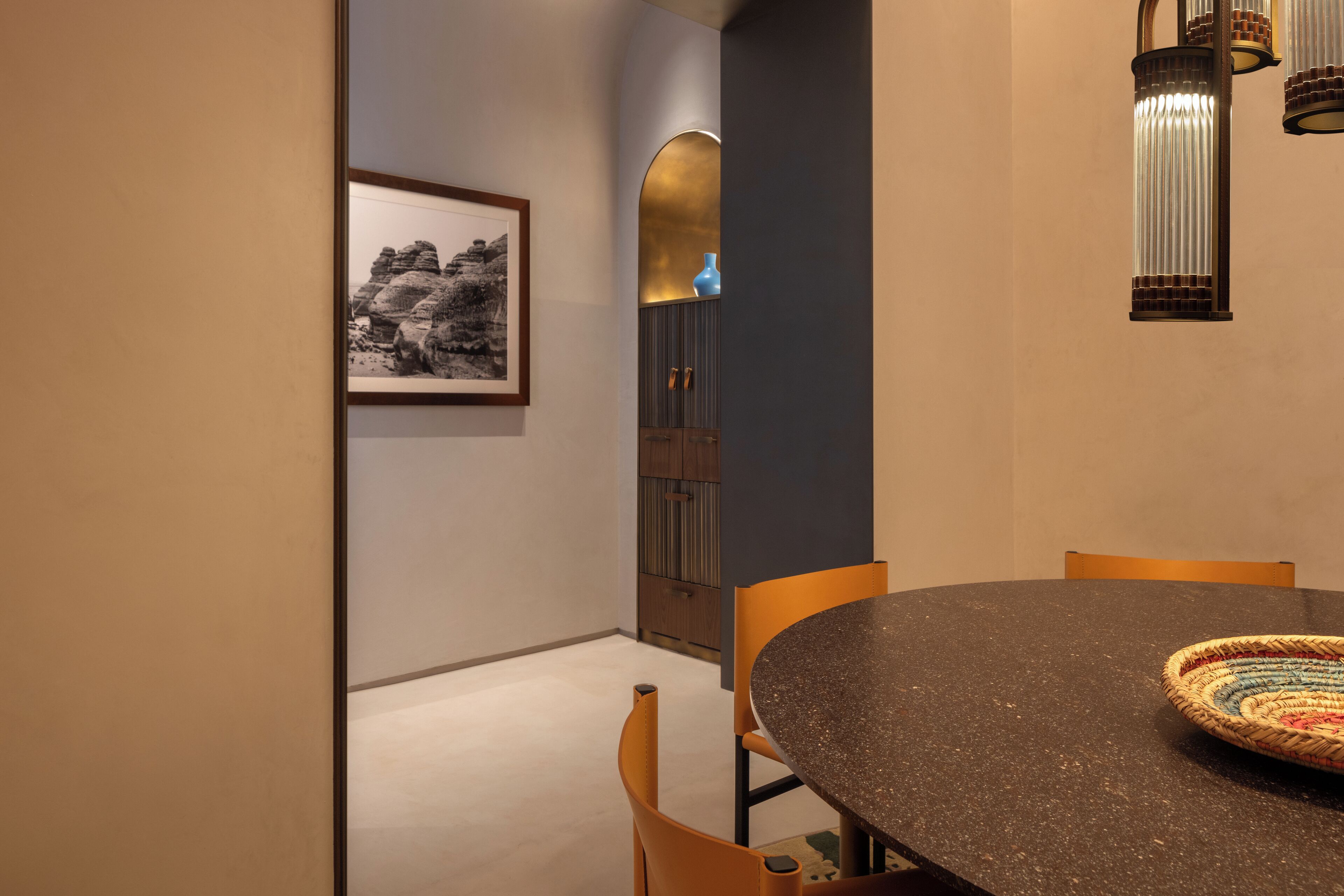 Un comedor con una mesa redonda, sillas, una fotografía enmarcada en la pared y un jarrón decorativo.