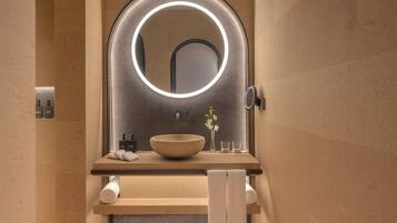Experience a serene bathroom retreat with a large round mirror, sleek countertop, and a beautifully arranged space.