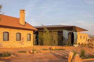 Una casa moderna con fachada de piedra, un añadido de cristal y un jardín ajardinado.