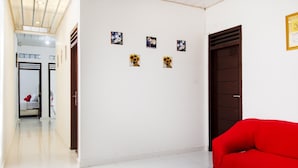 A hallway with a red sofa, white tiled floor, and a door with a dark frame.