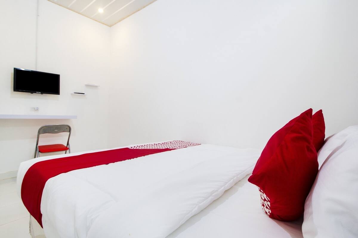 Una camera d'albergo con un letto, una televisione appesa al muro e una sedia.