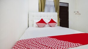 A neatly made bed with a red and white patterned blanket, a white headboard, and two red pillows.
