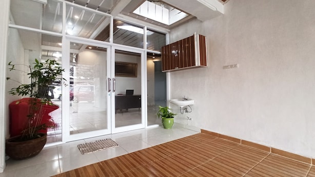A spacious room with a large sliding glass door leading to a balcony, a wooden floor, a green potted plant, and a white sink.