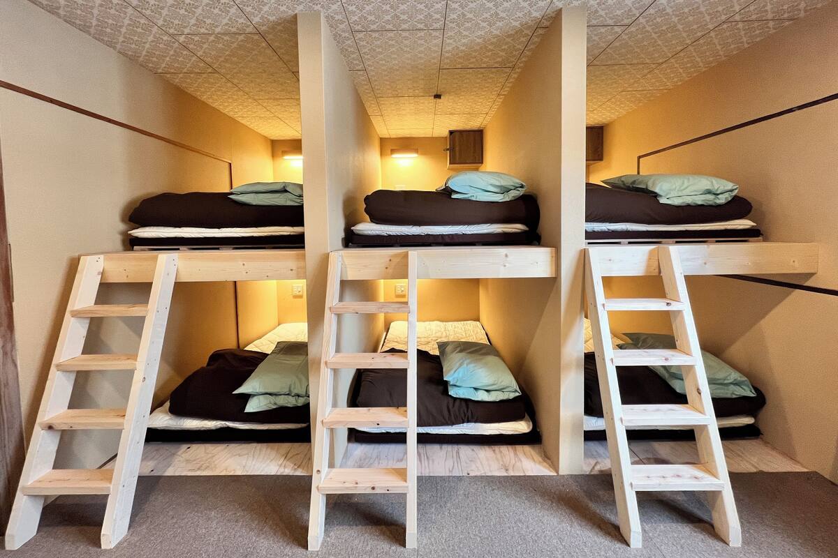 Ein Schlafsaalzimmer mit Etagenbetten und Holzleitern.