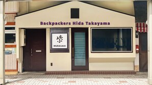 Rakennuksessa on kyltti, jossa lukee ”Backpackers Hida Takayama”, ja toinen kyltti, jossa lukee ”MURASAKI”.