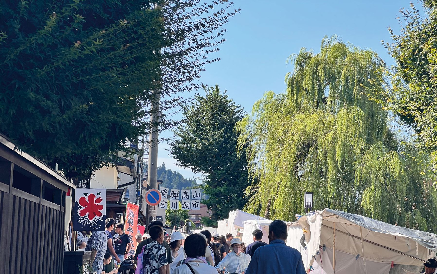 A bustling market scene with people walking and vendors displaying goods.