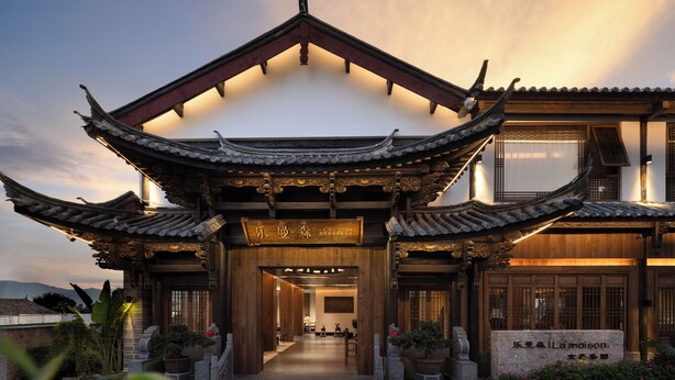 A traditional Chinese building with a prominent entrance, wooden doors, and a sign indicating it is a hotel. - LA MAISON . View Resort (Lijiang)